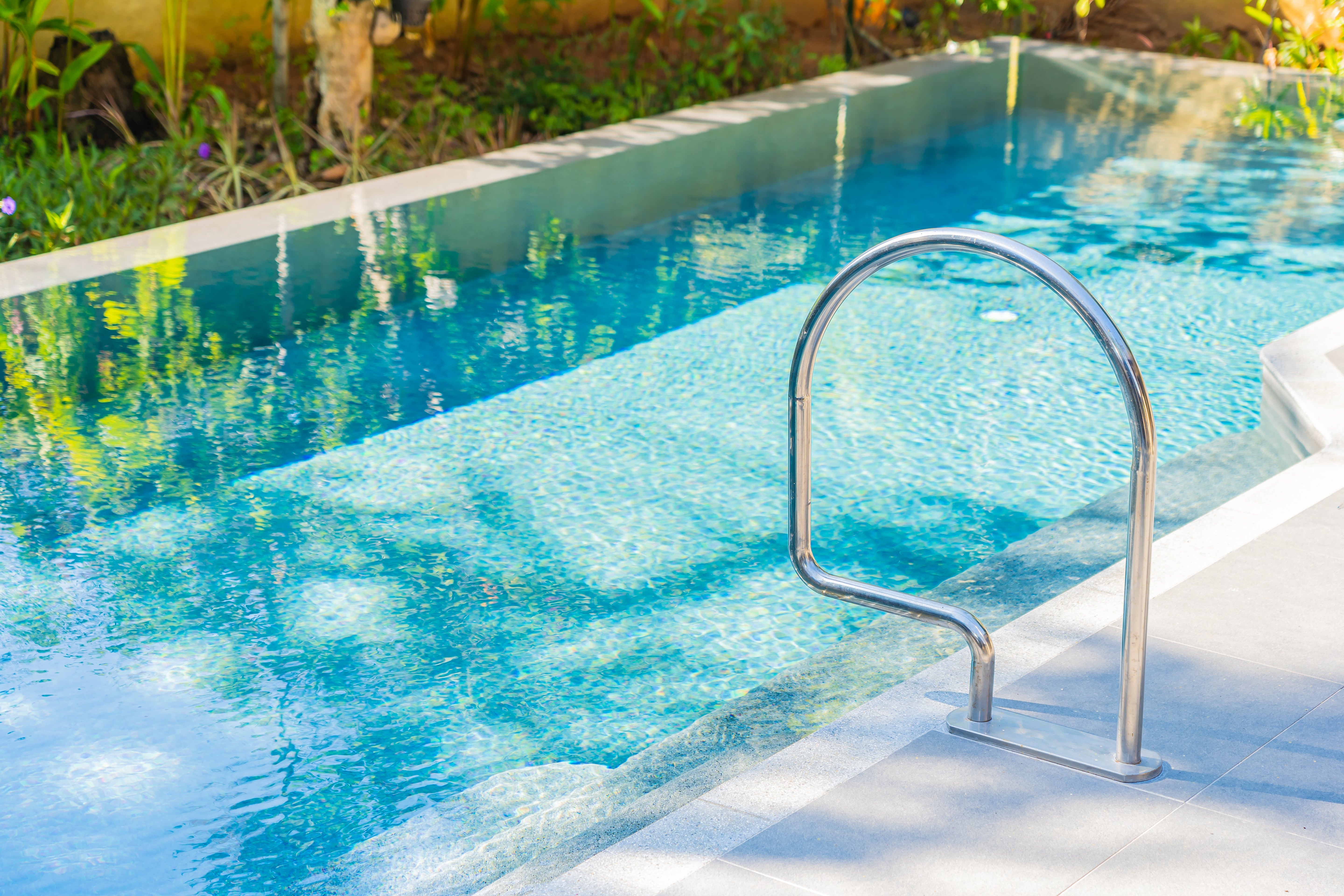 Glossy blue ceramic pool tiles installed along the waterline of a bright outdoor swimming pool.