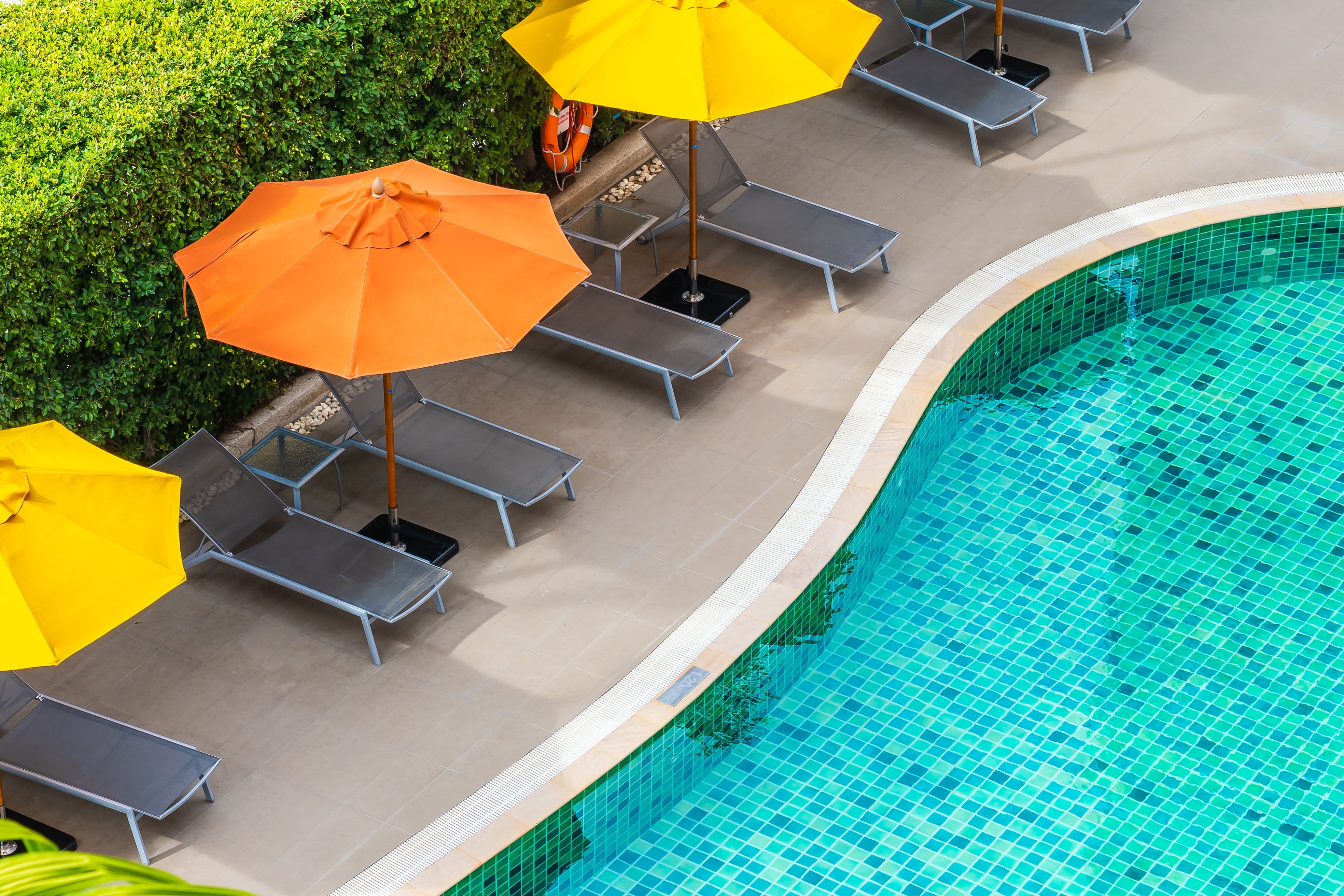 Iridescent blue glass pool tiles shimmering along the waterline of a luxury outdoor swimming pool.
