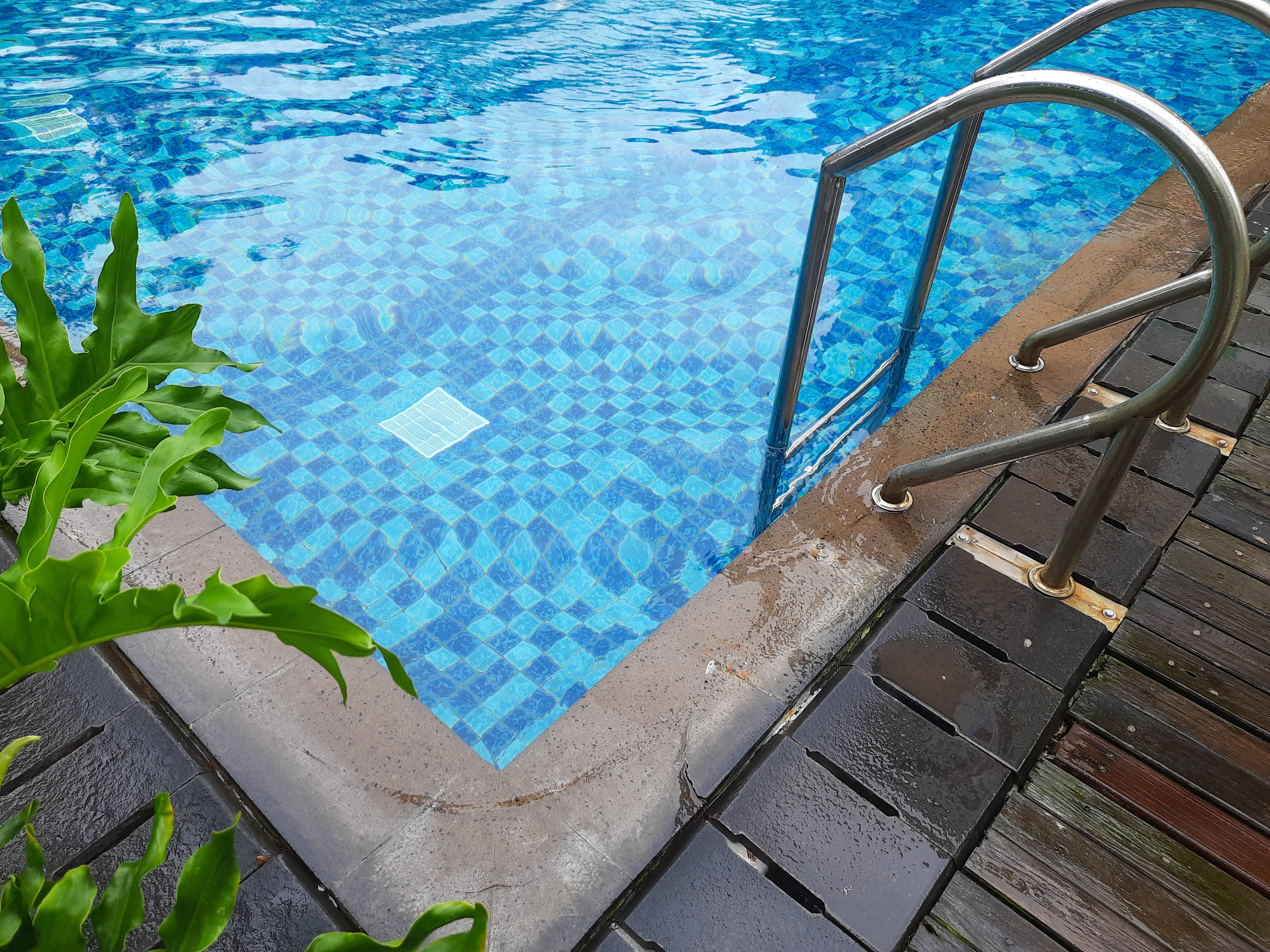 Blue mosaic pool tiles installed along the waterline and spa edge of a luxury outdoor swimming pool.