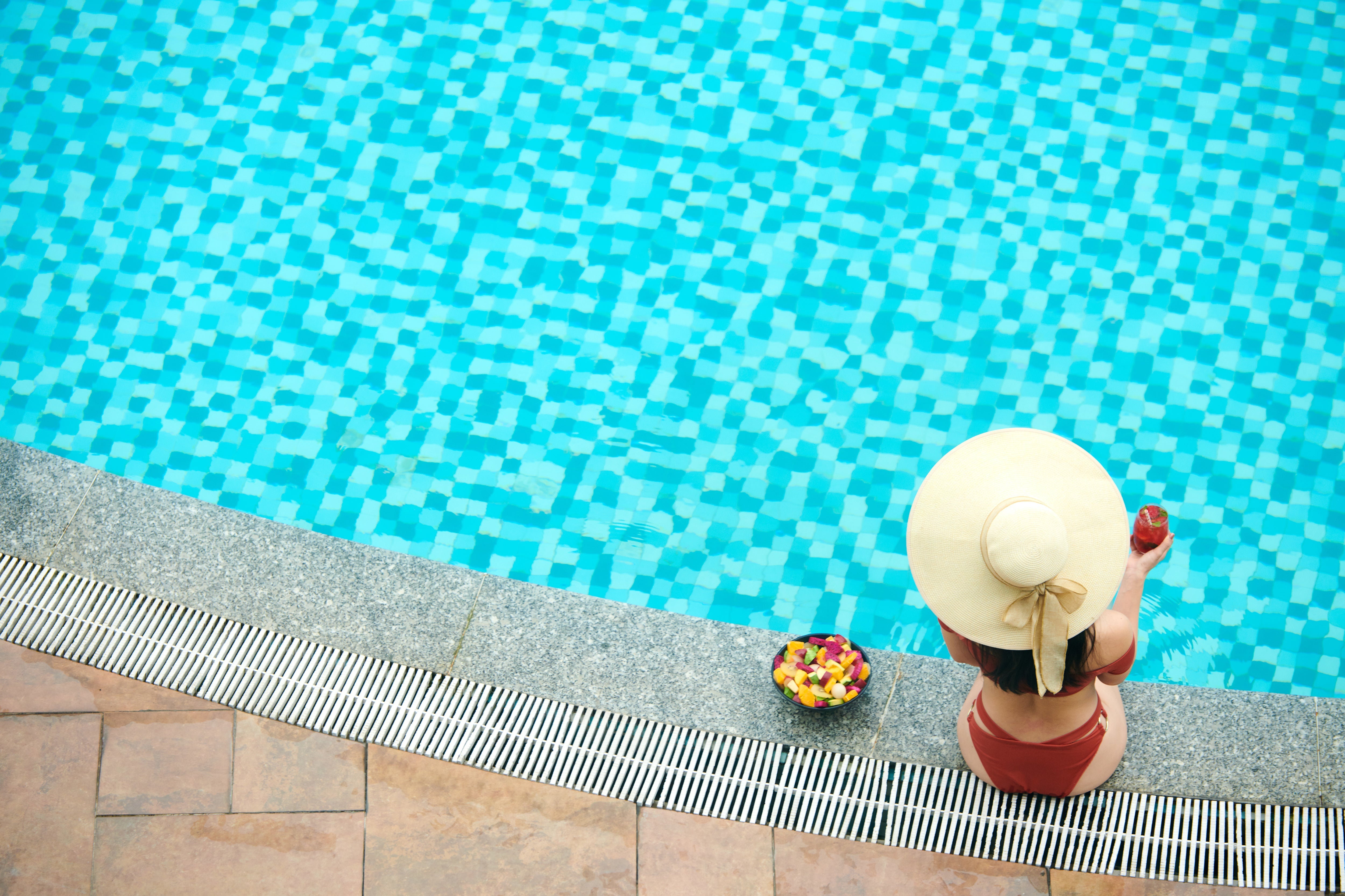 Blue mosaic pool interior tiles covering the steps and floor of a clear luxury swimming pool.