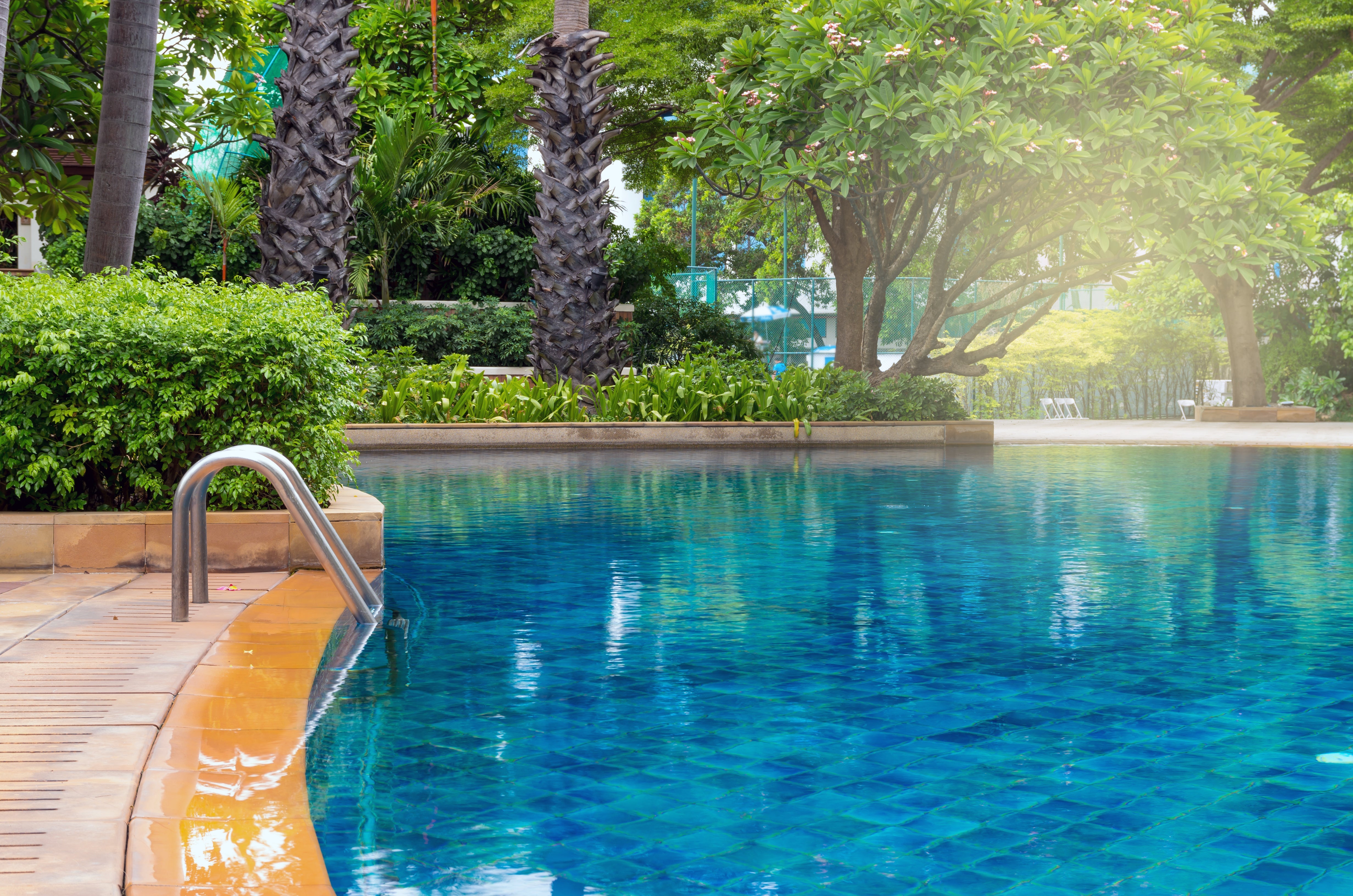 Recycled blue glass mosaic pool tiles shimmering along the waterline of a modern outdoor swimming pool.