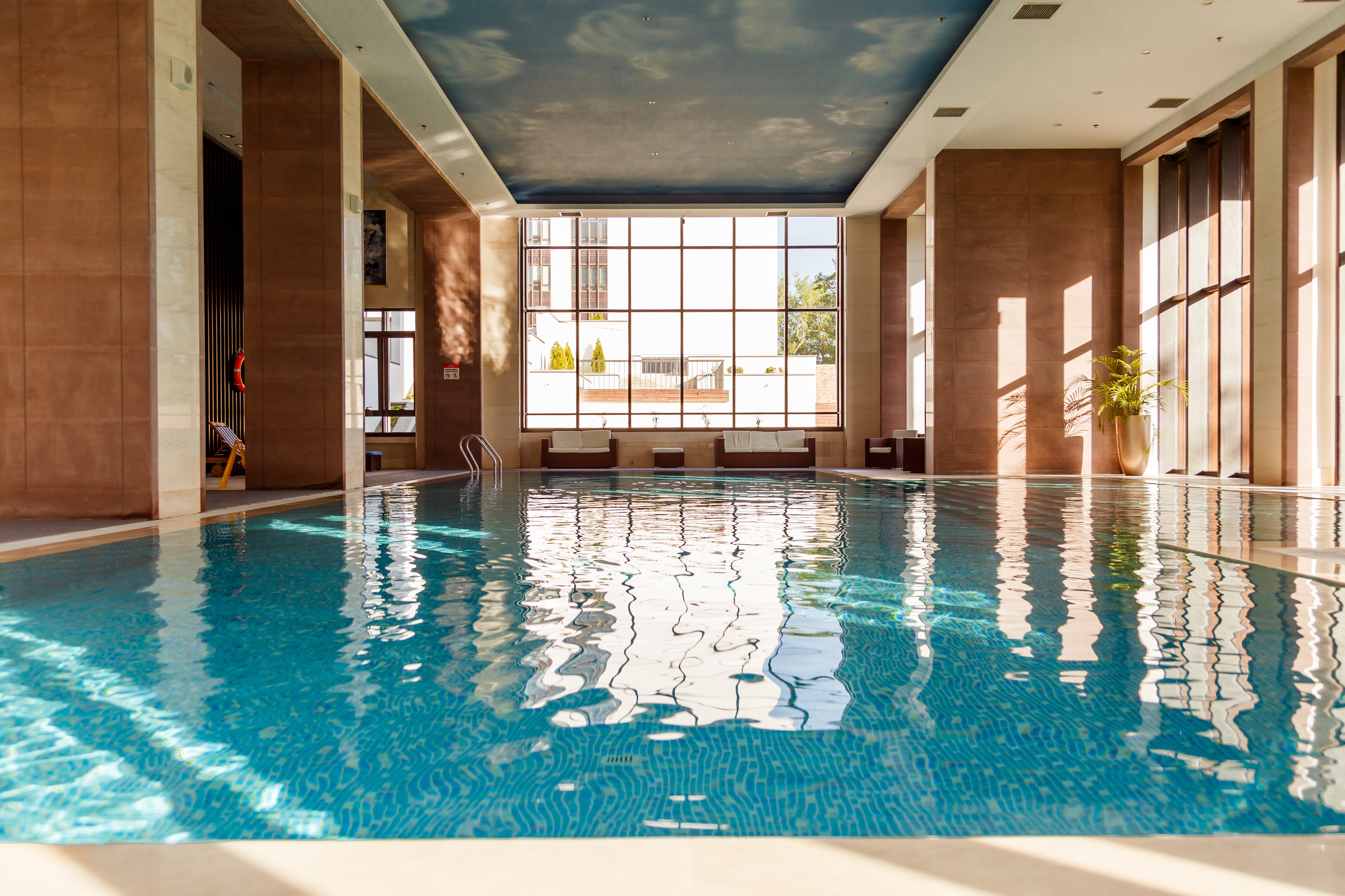 Blue mosaic spa tiles wrapping a raised outdoor spa beside a luxury swimming pool.