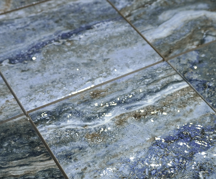 Close-up of Storm Blend blue porcelain pool tile underwater, showing marbled grey-blue veining and grout joints.