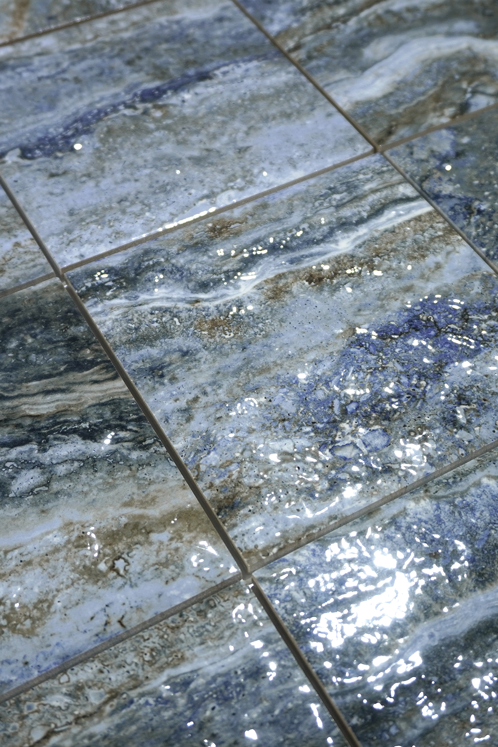 Close-up of glossy marbled blue porcelain tile with indigo, cream and bronze veining.