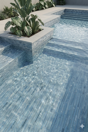 Linear Ocean Blend blue glass mosaic tile cladding a raised pool wall and planter beside a stone pool deck.