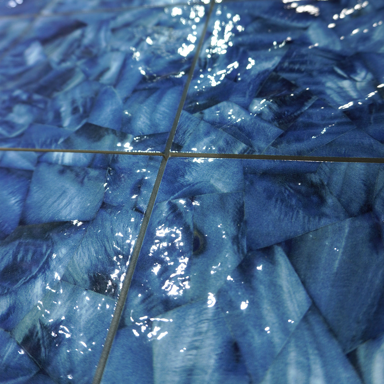 Close-up of Ocean Blue Artisan 6x6 porcelain pool tile underwater, showing brushed blue glaze and grout joints.