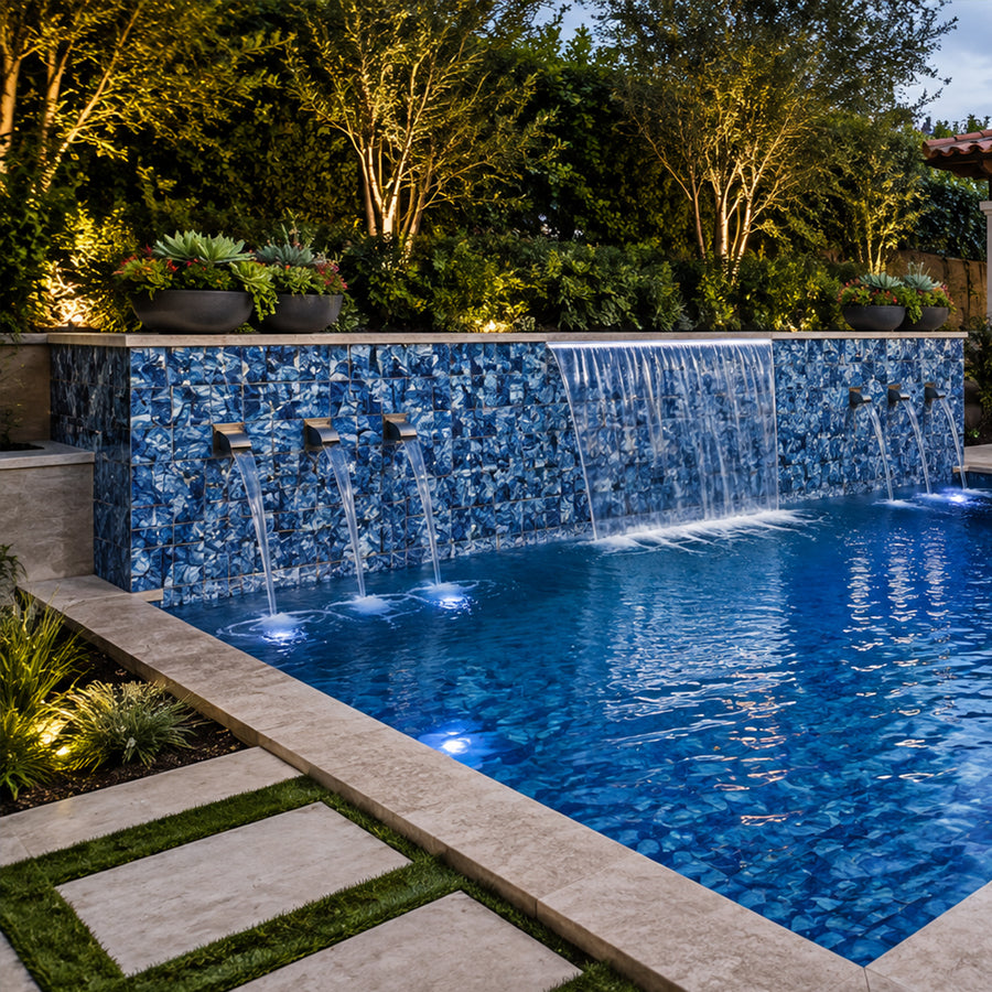 Pool at night with sheer-descent spouts set into an Ocean Blue Artisan 6x6 porcelain tiled wall.