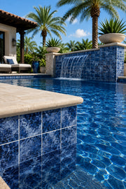 Mediterranean villa pool with a waterfall wall tiled in Ocean Depth Blue 6x6 porcelain.