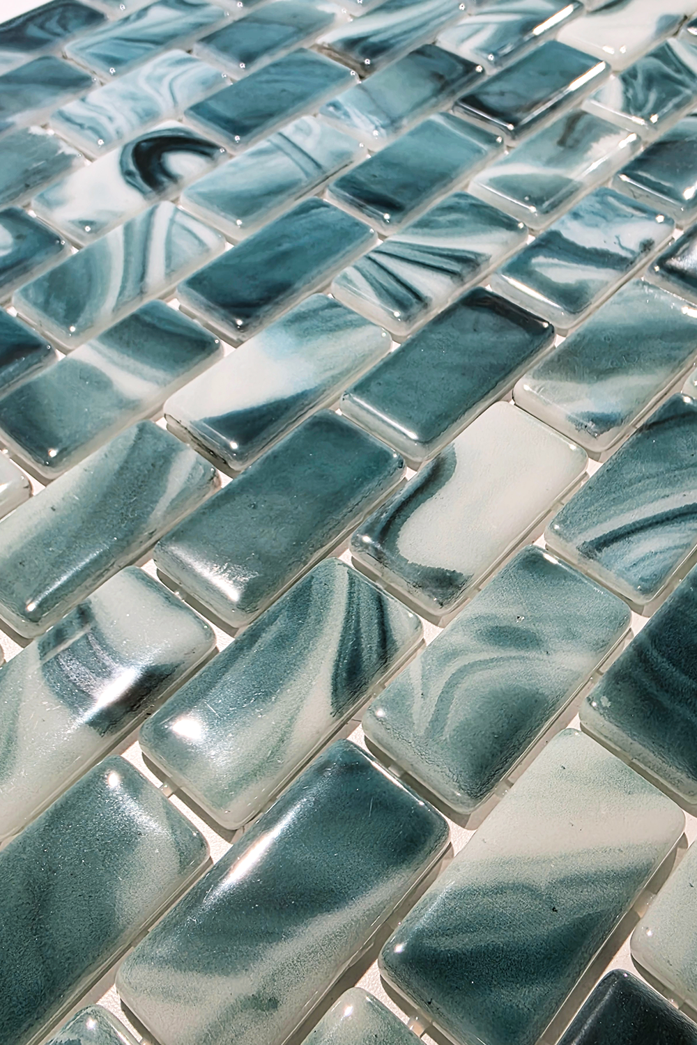 Angled detail of Seafoam Green Swirl recycled glass mosaic tile showing the marbling and mesh-mounted brick-set layout.
