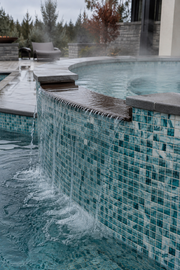 PT-9803 seafoam green glass mosaic tile installed on a raised spa spillway with flowing water and teal, aqua and white tones.